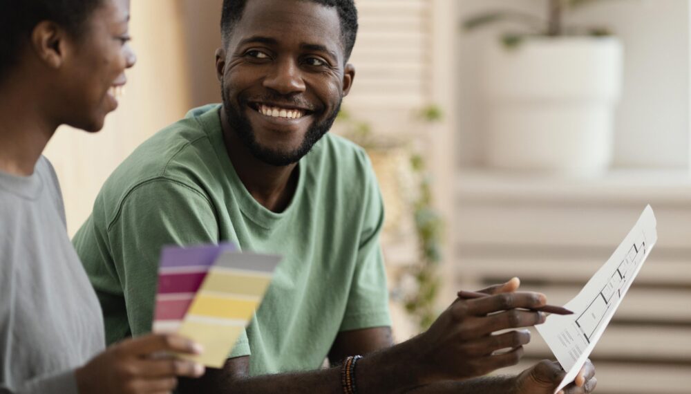 smiley-couple-making-plan-using-color-palette-redecorate-house